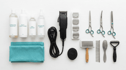 Professional dog grooming tools and equipment laid out on a clean white surface
